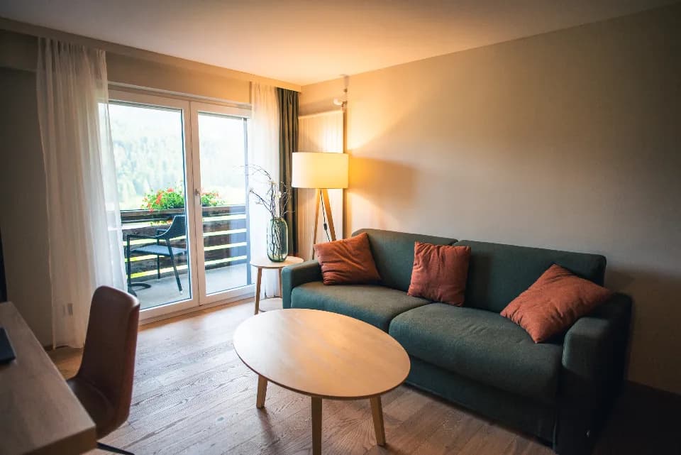 Balkonlu, sıcak ışıklı bir otel odasında kanepe ve sehpa